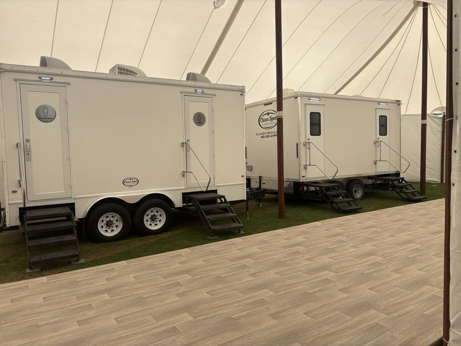 Clean Spot luxury restroom trailer set up beside an event tent on the water
