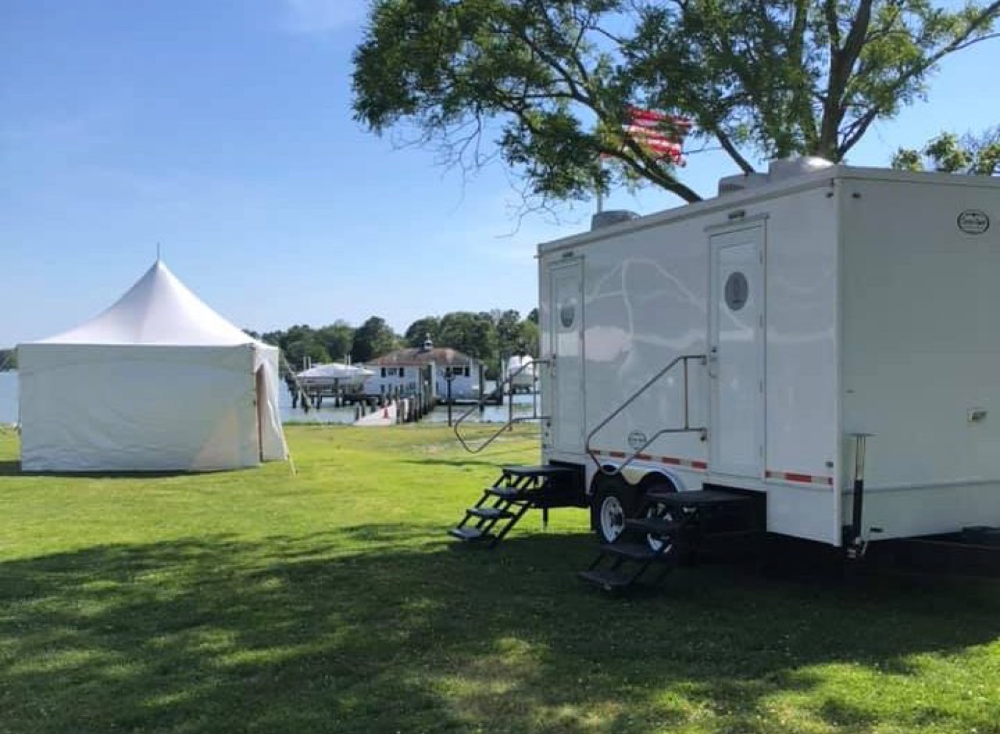 Clean Spot restroom trailer beside an event tent overlooking the water