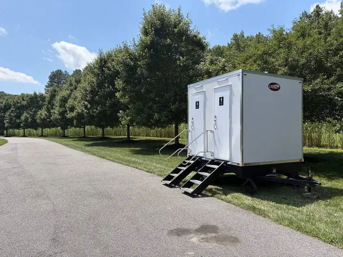 Two station restroom trailer set up along a tree lined drive at a private estate